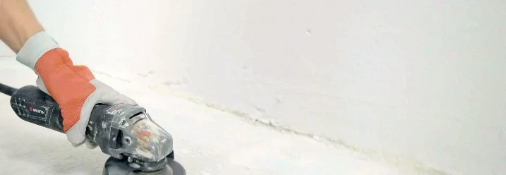 Hand mit Winkelschleifer auf Betonboden